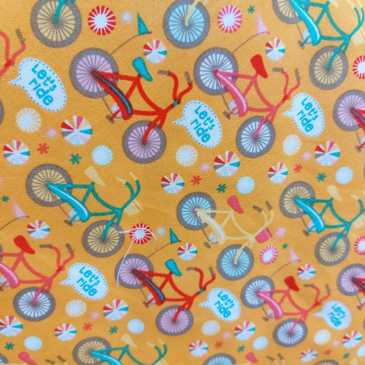 A dark yellow background shows all different coloured bicycles with the words let's ride.