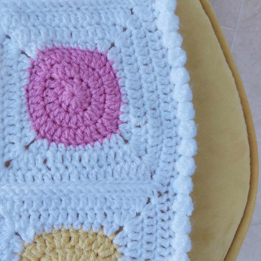 white bobble edge of a handmade baby blanket with pink and yellow circles surrounded by white