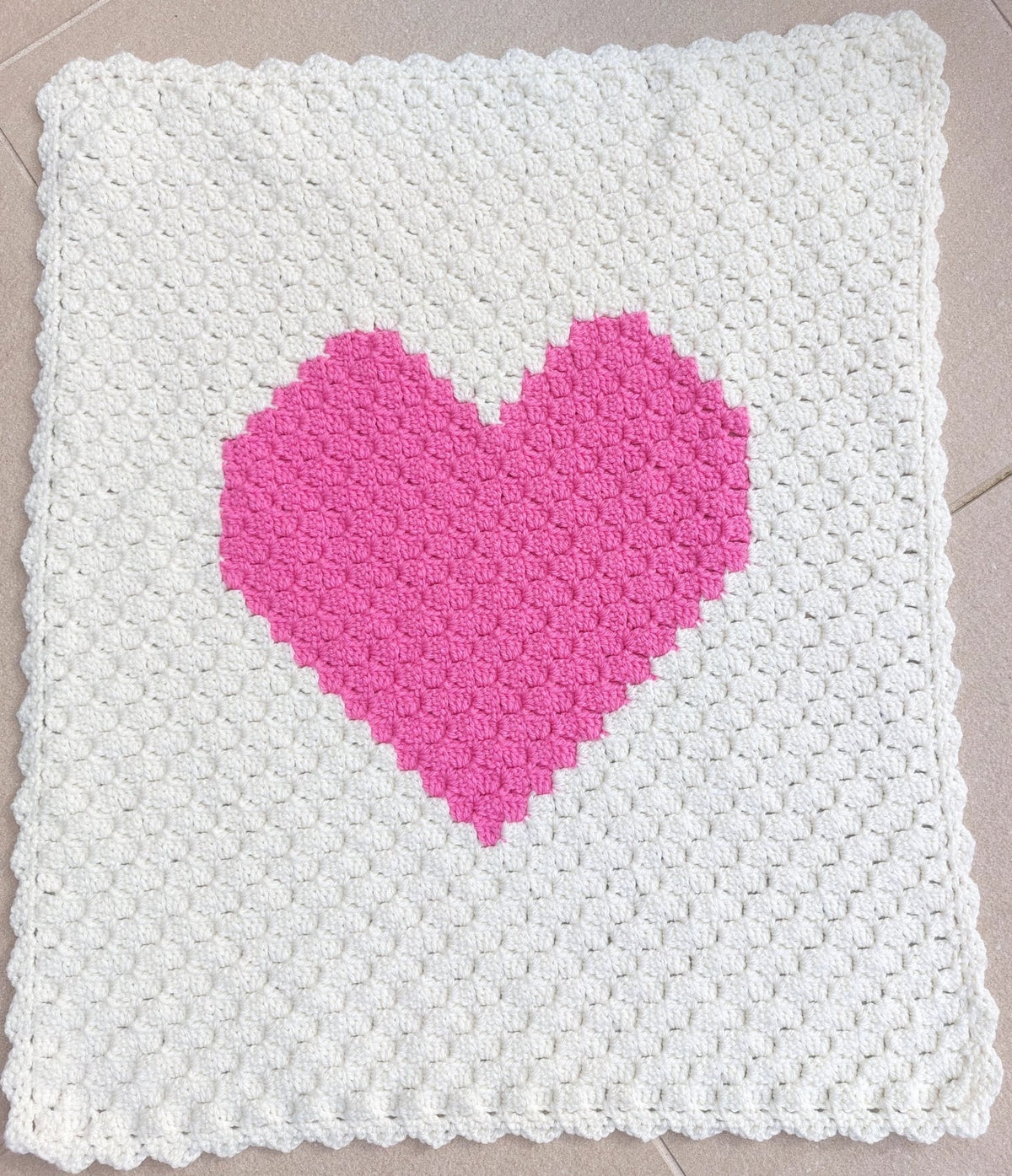 the handmade pink heart crocheted baby blanket laid of flat