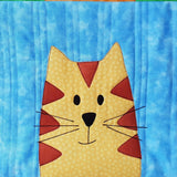 bright blue background with a yellow cat with brown triangles on the face