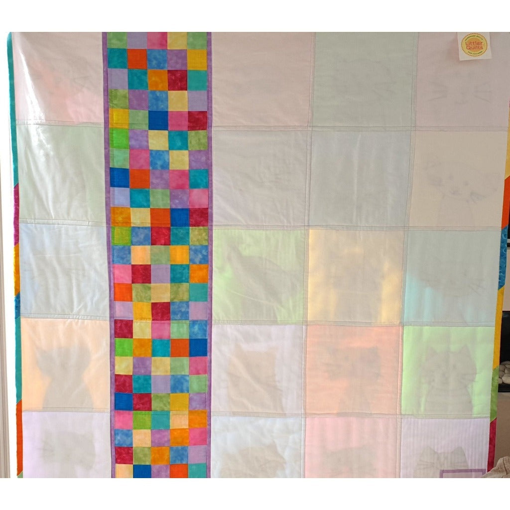 the back oft he cute cats quilt. Half of the quilt is plain cream and a section is made up of small patchwork squares sewn together