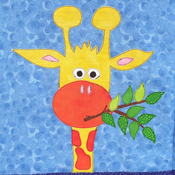 close up of a blue fabric background with a giraffe head and neck of yellow and orange spots. The giraffe is smiling and eating a branch with leaves on it.