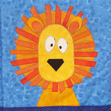 a blue fabric background with a bright orange lion with an orange mane and a yellow face with big white eyes and a black nose