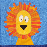 a blue fabric background with a bright orange lion with an orange mane and a yellow face with big white eyes and a black nose