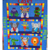 The jungle quilt front in blue fabric with 4 elephants, a purplr hippo, a smake wrapped around a tree, a smiling croc and a lion