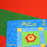 the corner of the quilt front showing the name of the boy it was made for solded over to show the red and green striped back