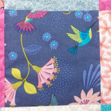 A close up of one of the blue fabric patches showing a brightly coloured hummingbird and flowers