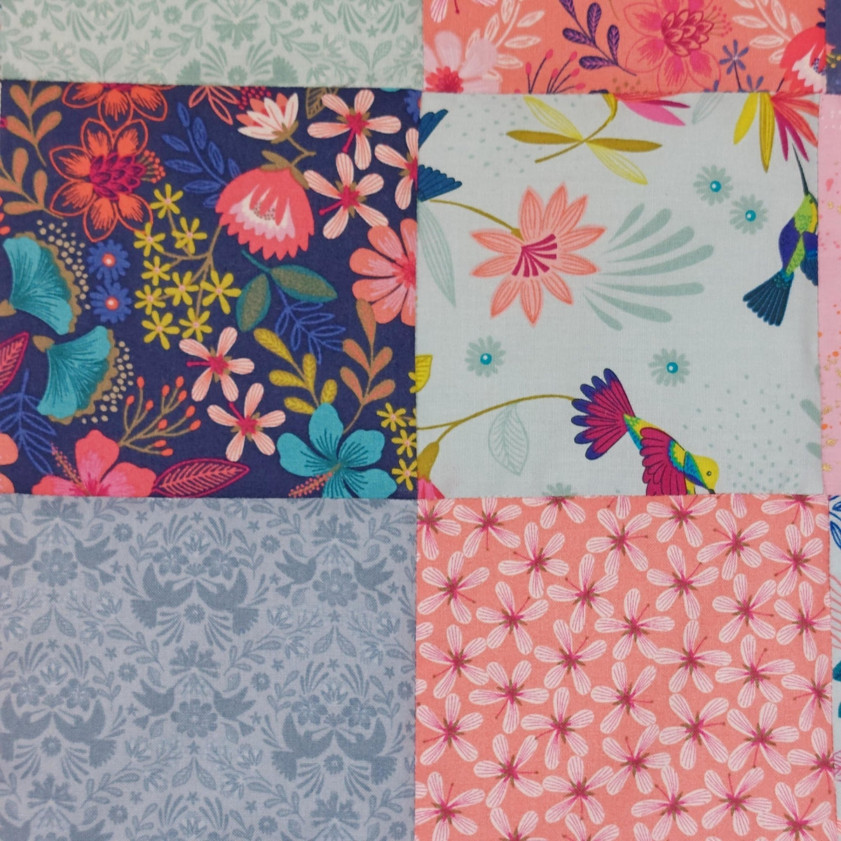 close up of 4 square fabric patches with brightly coloured flowers and hummingbirds