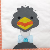a white fabric background with a grey smiling emu wearing a blue bow tie on the land down under quilt