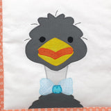 a white fabric background with a grey smiling emu wearing a blue bow tie