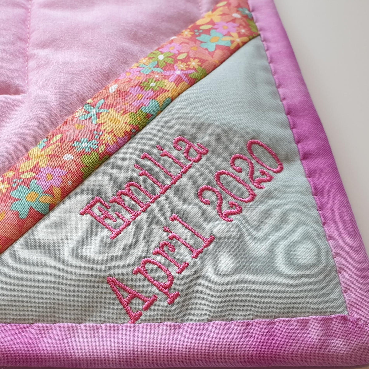 the corner of the back of the land down under quilt showing a label with the name of the baby girl and her birthday