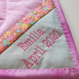 the corner of the back of the land down under quilt showing a label with the name of the baby girl and her birthday