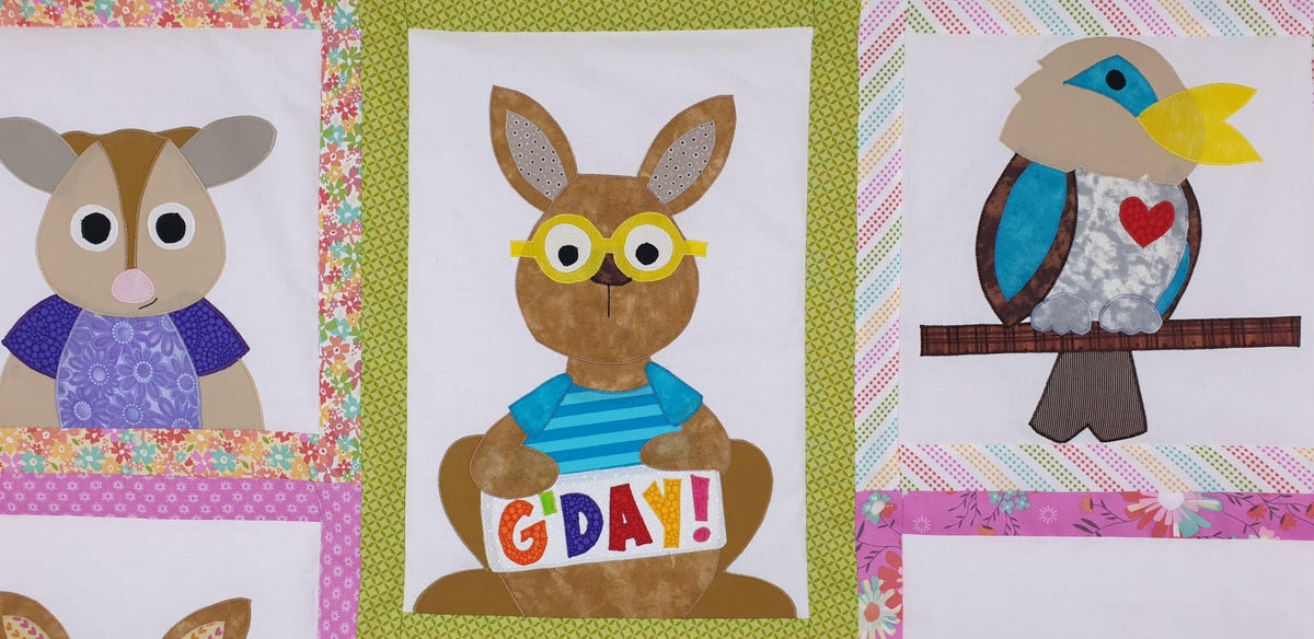 the top portion of the quilt showing a possum, a kangaroo with a sign saying g'day and a kookaburra  bird on a branch