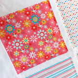A big patchwork squares showing a pink background with different coloured daisy flowers 