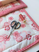 the back of the quilt showing a pair of scissors and thread where the binding has just been sewn