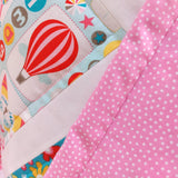 the pink and white dots backing to the quilt is seen turned over to show the front of a hot air balloon