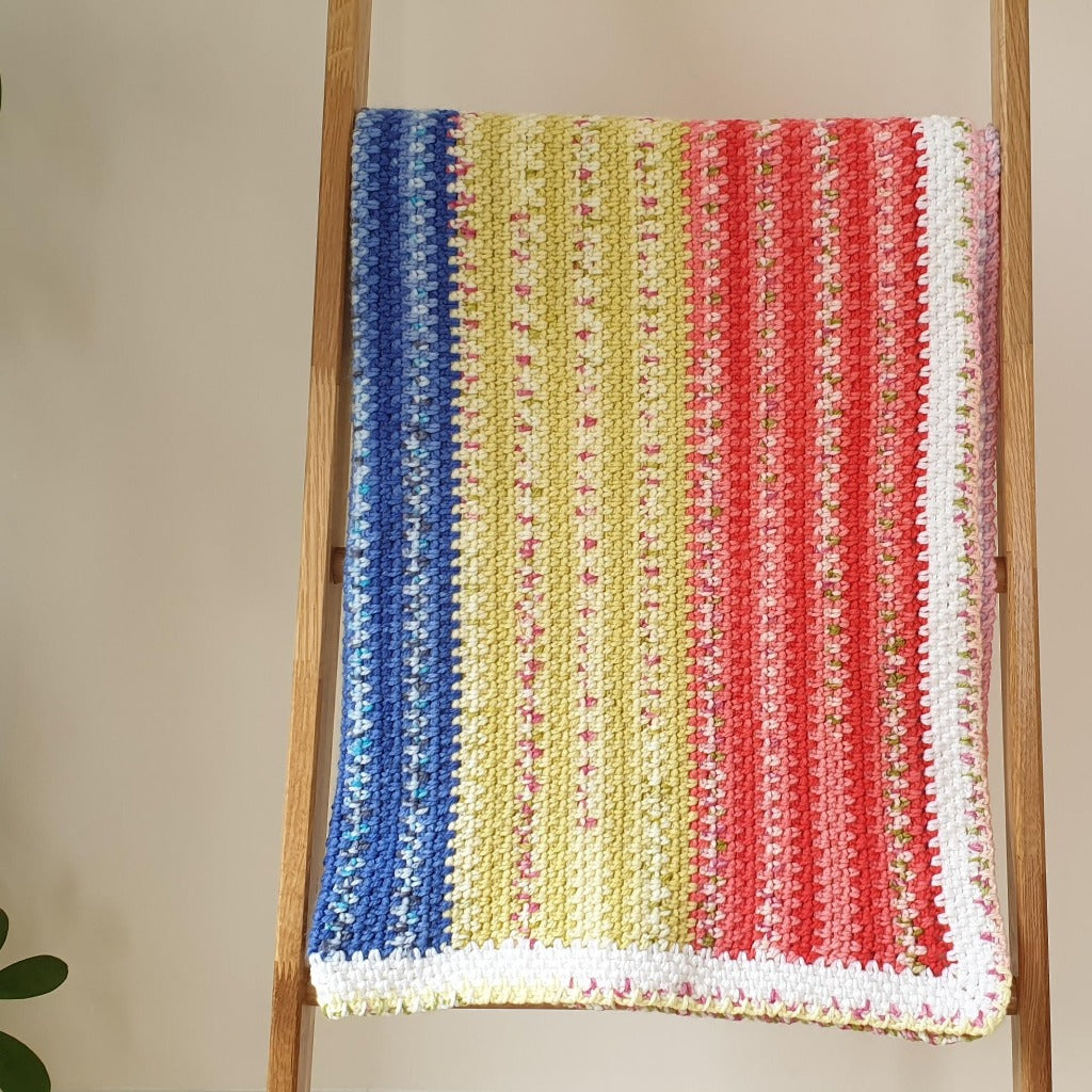 the handmade baby blanket folded over a large wooden ladder