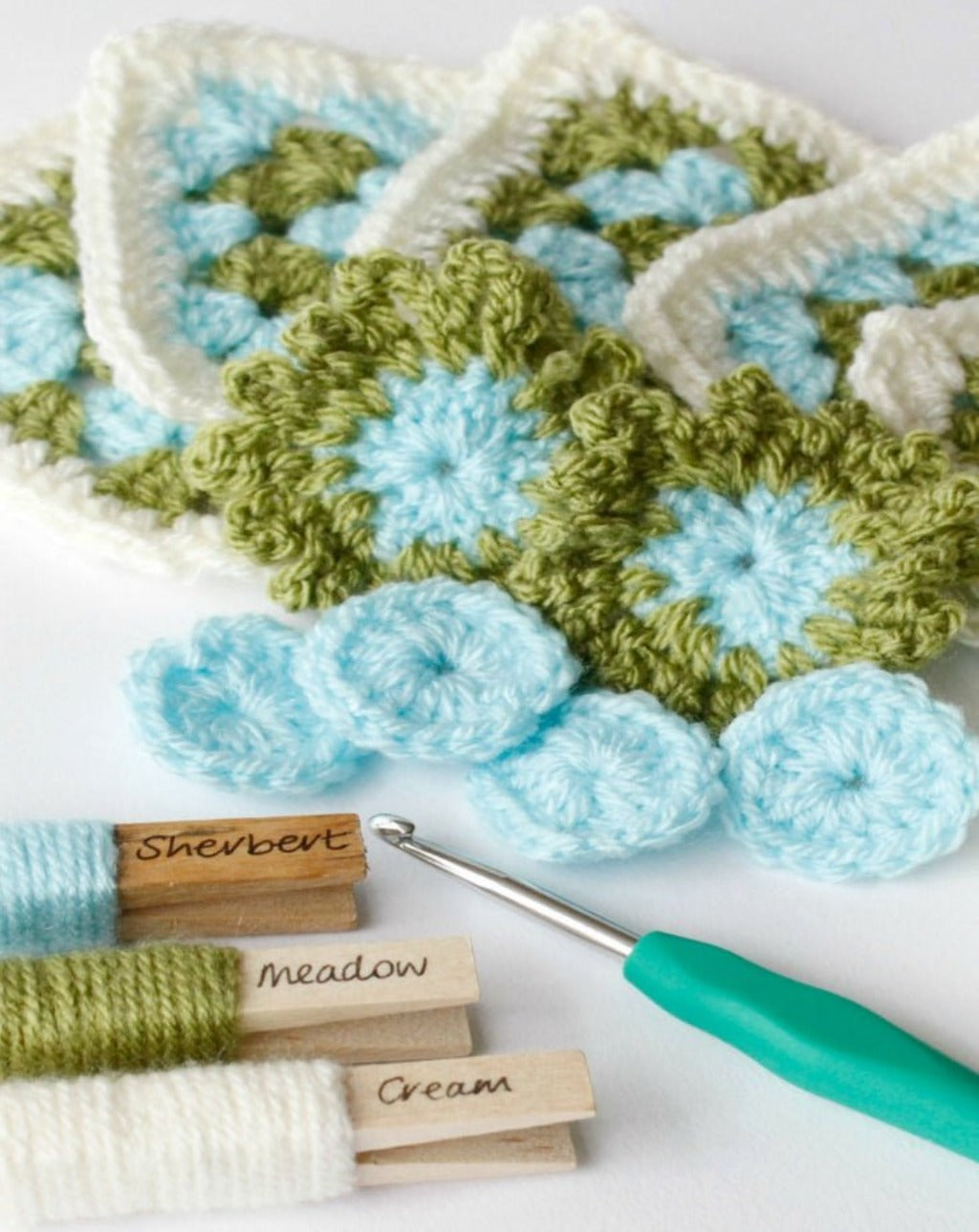 the start of the crochet granny squares which make up the blanket with clothes pegs showing their colours
