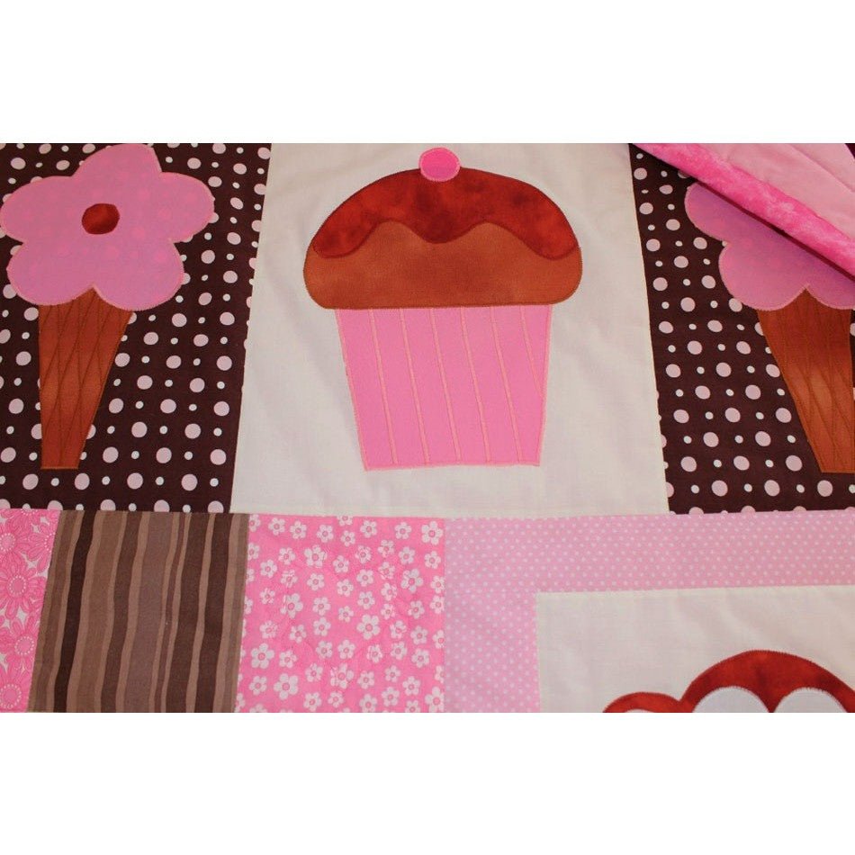patchwork squares of pink, cream and brown. There are brown and pink ice creams and a large pink cupcake sewn on the squares