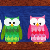 a pink owl and a green  owl sitting on a brown branch