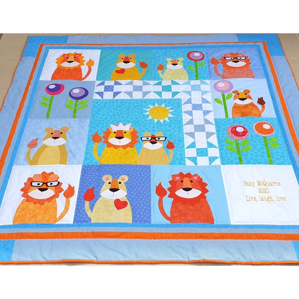 the whole jungle quilt showing the lions, lionesses and cubs with flowers and also embroidery of the name and birth date of the baby