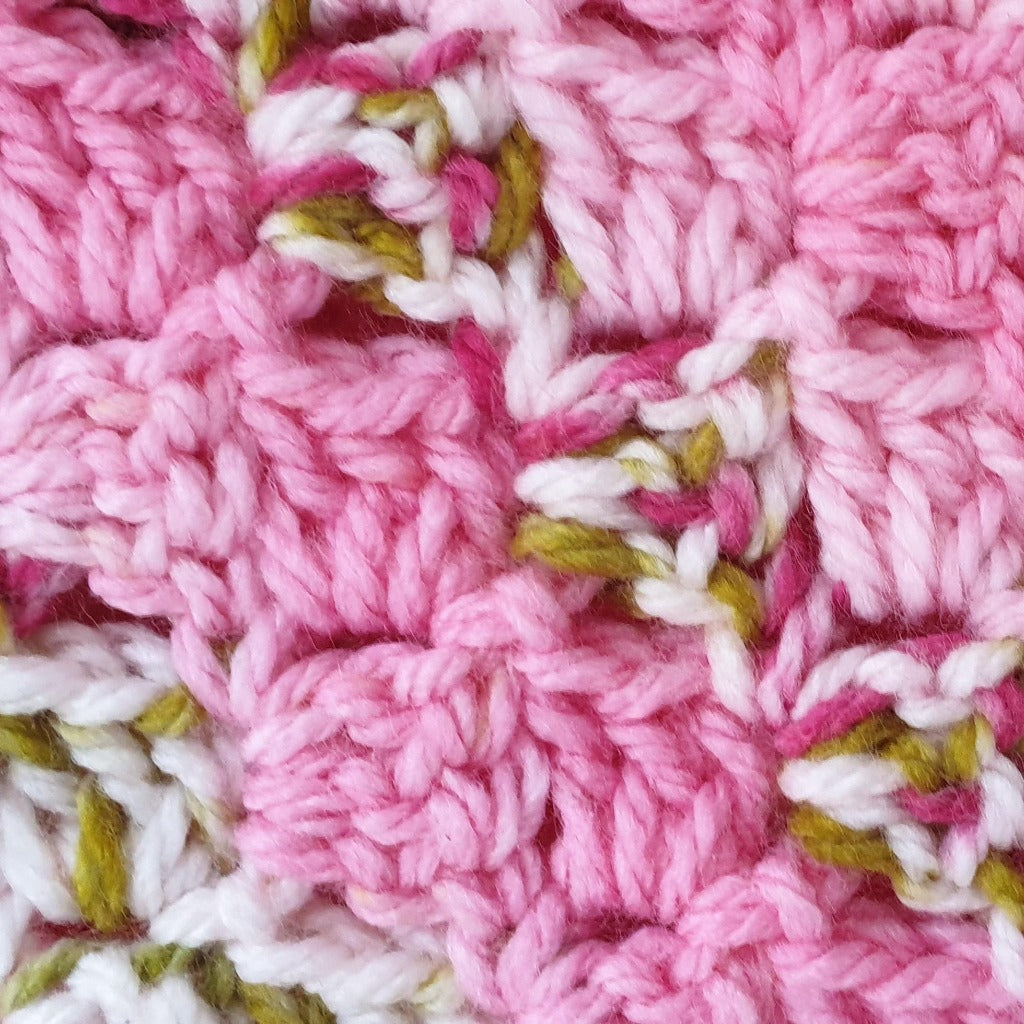 close up of the pink and green stitch on the handmade crochet baby blanket