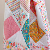 the girl crazy quilt draped over a quilt ladder so you can see the large patches of the quilt