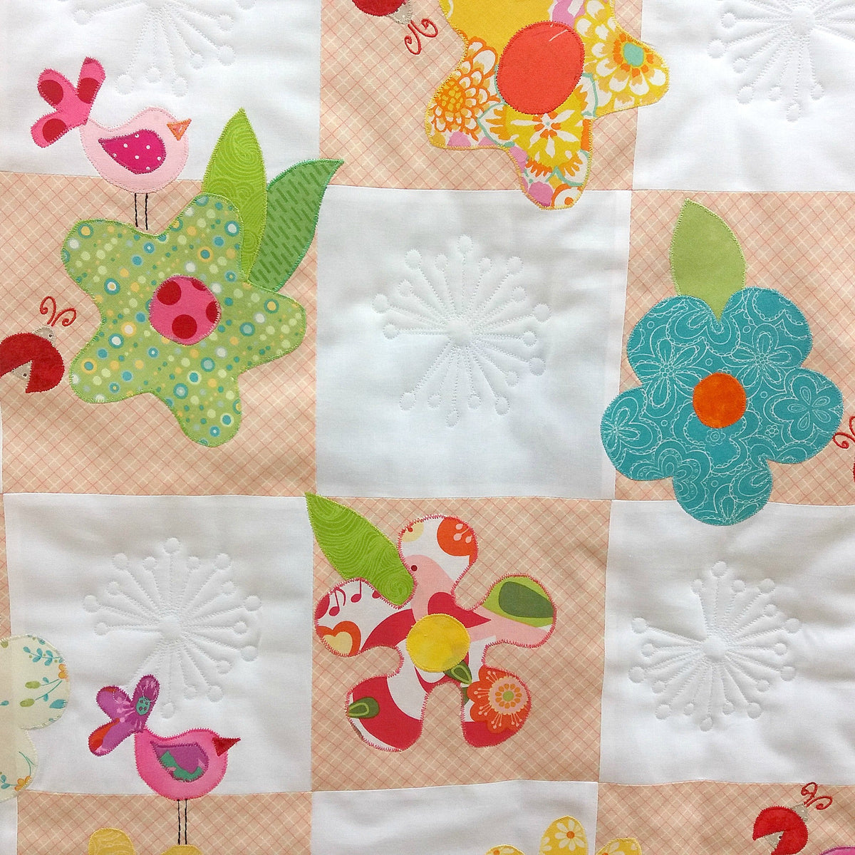 peach and white patchwork squares with coloured flowers and birds 