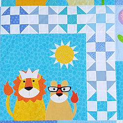 a blue fabric background shows a lion wearing a crown with his  cub and a sun surrounded by a patchwork border of white and different blues 