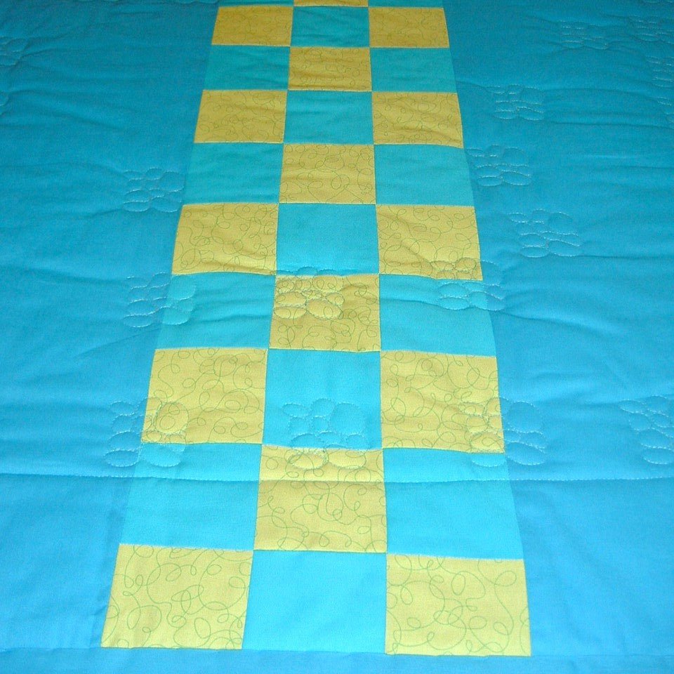 the back of the dinosaur quilt in blue with the middle being a chequer board effect of blue and green