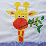 A yellow giraffe with bright orange spots, smiling while eating a branch with green leaves