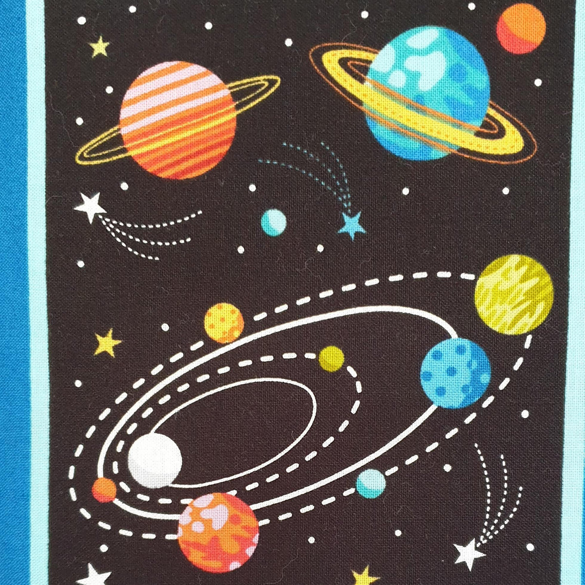 a printed cotton quilt showing orange, blue and yellow planets, some with rings around the planet and shooting stars all on a black background