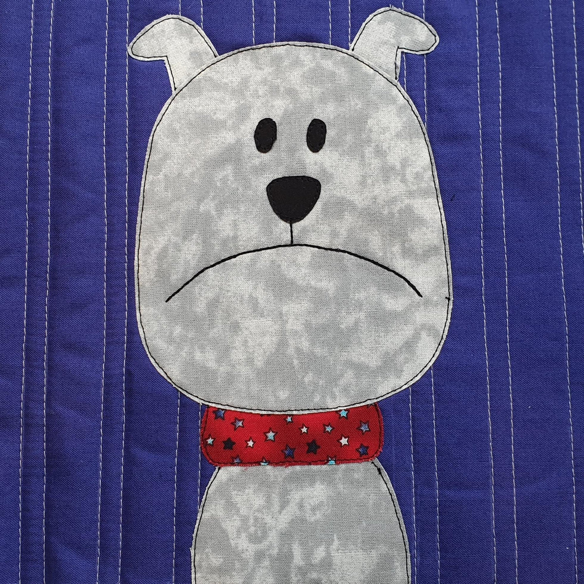 a plain purple background has a grey dog with a red and stars collar. The dog looks grumpy with his mouth turned down.