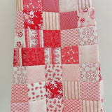 the raspberry flowers patchwork quilt draped over a quilt ladder