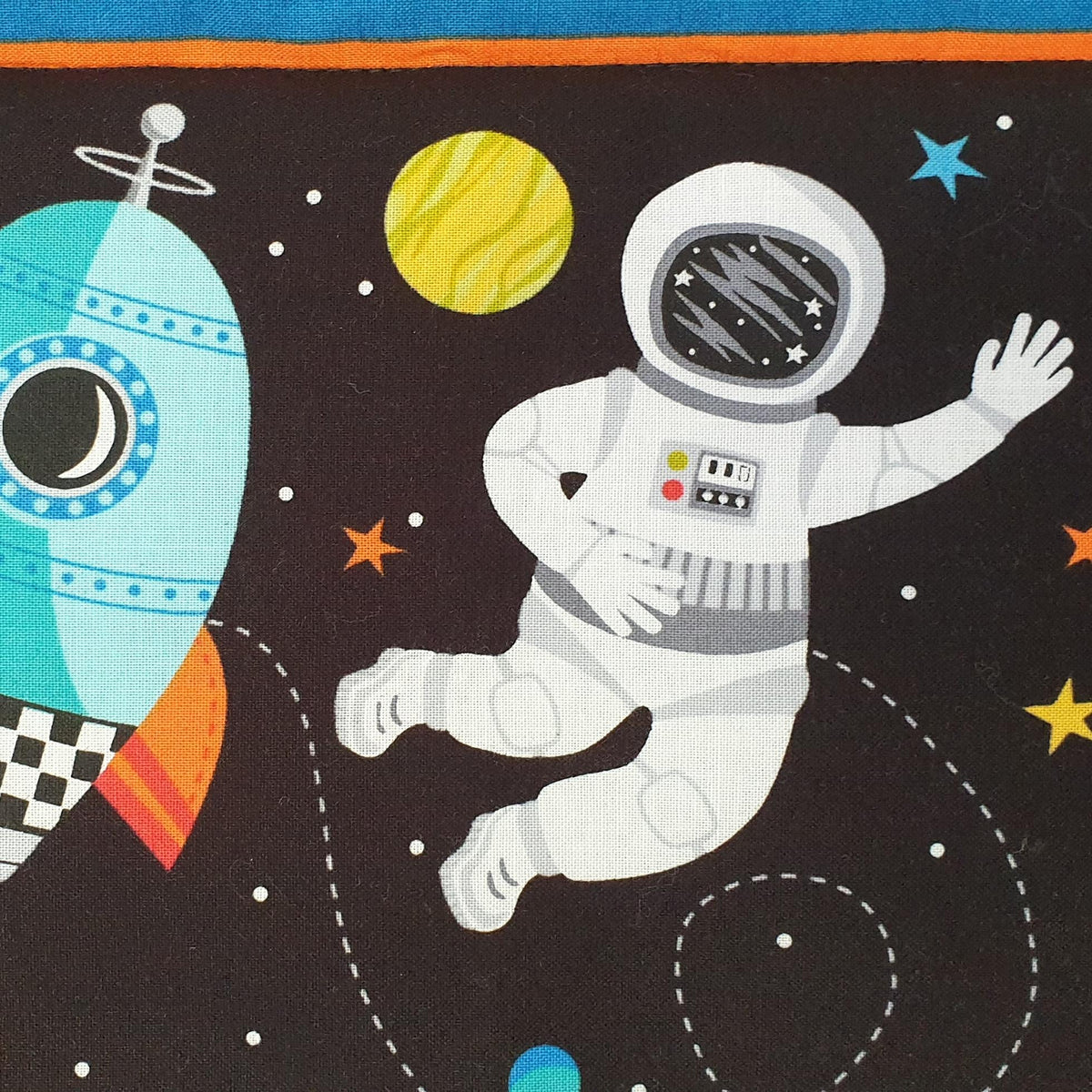 a colourful printed cotton panel quilt showing a spaceman in a white suit floating in space with a yellow planet and colourful stars