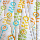the back of the sunshine quilt made of white fabric with green , blue, orange and yellow flowers