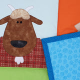 a goat with a brown head and white beard and with the blue reverse fabric of the quilt turned over