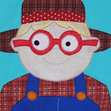 the smiling face of a farm boy on a farm quilt wearing blue dungarees, red glasses and a brown hat