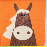 a brown spotted horse on a farm quilt with a bright orange background with a cream mane, muzzle 