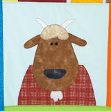a brown goat on a farm quilt with a white beard and a red check body