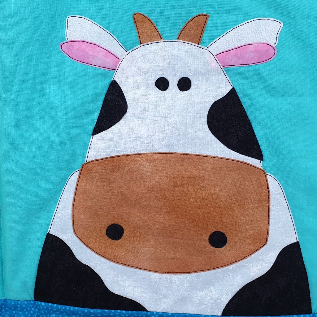 a blue background with a large black and white cow face with pink ears and brown horns